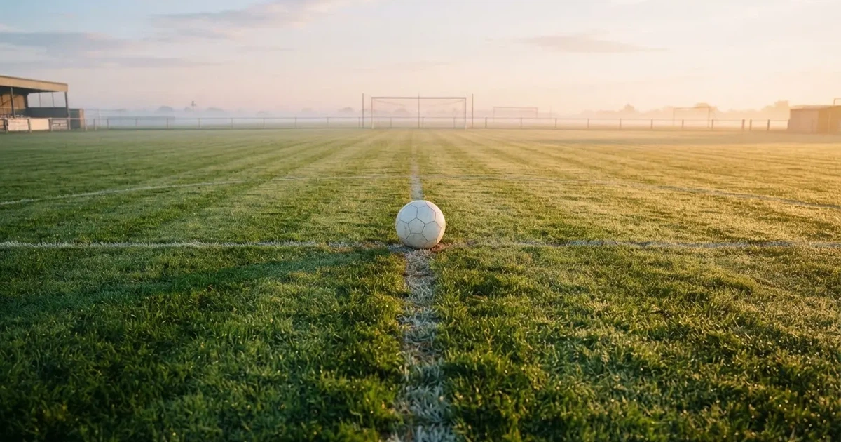 Un balón en el punto central de un campo de césped a la luz de la mañana