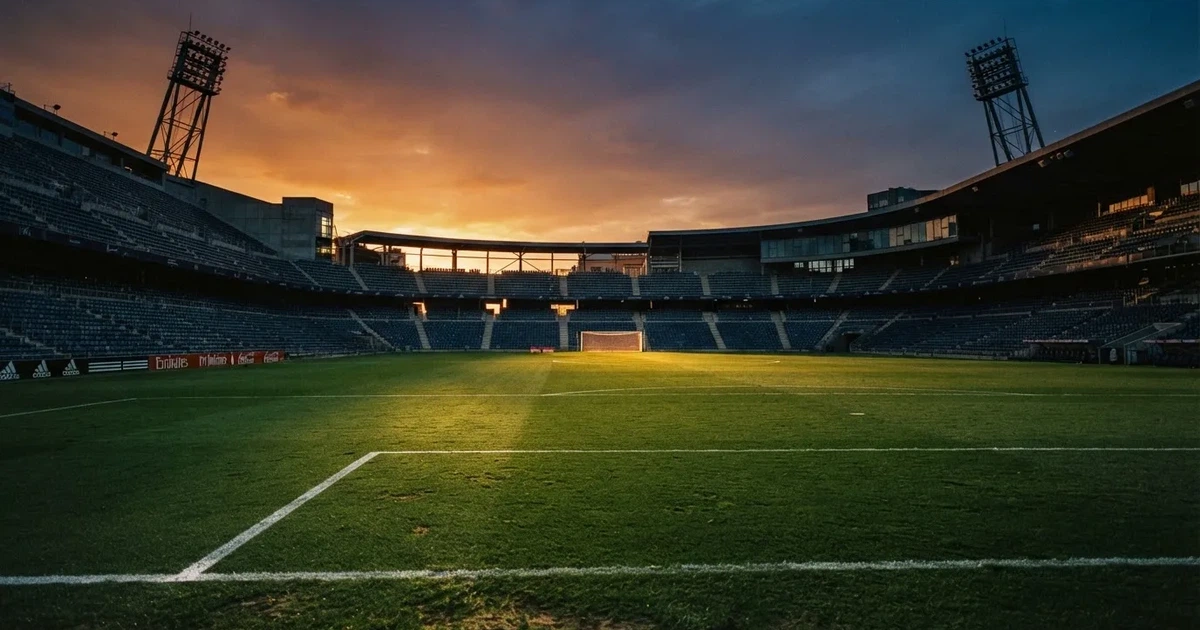 Un estadio de fútbol vacío con torres de iluminación al atardecer