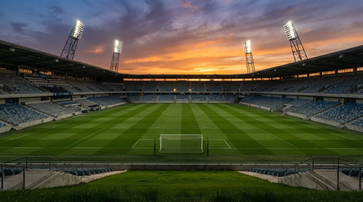 Un estadio de fútbol vacío con torres de iluminación al atardecer